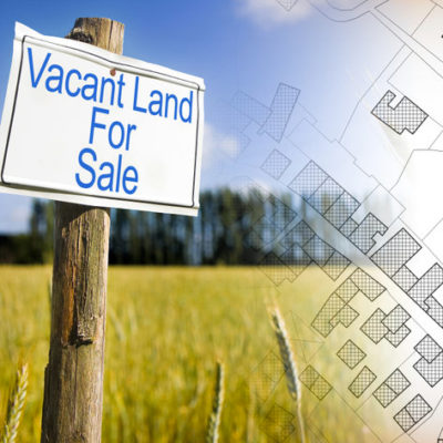 Advertising metal signboard in a rural scene with Vacant Land for Sale written on it and an imaginary cadastral map of territory with buildings, fields and roads against a green area